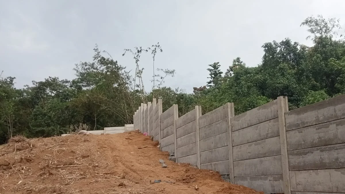 Jasa pagar panel beton Lebak: pagar beton pracetak lurus di tepi lahan tanah merah, hasil kerja PT Adiwangsa Prima Konstruksi