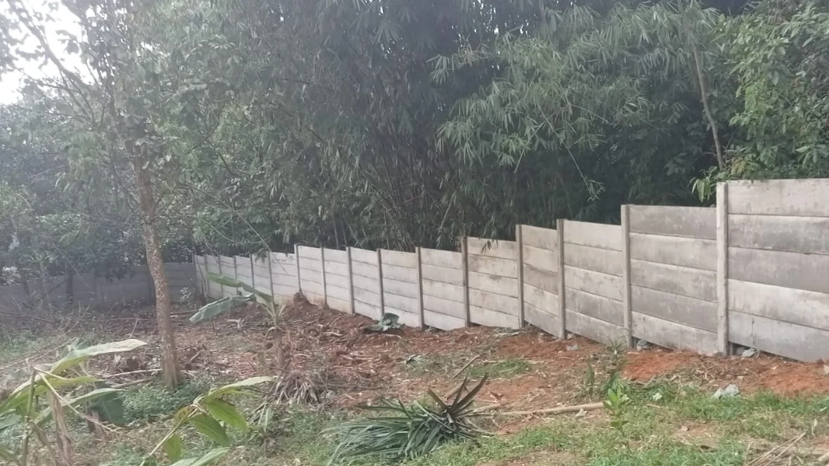 Pagar beton pracetak berundak mengikuti kontur lahan di tepi kebun